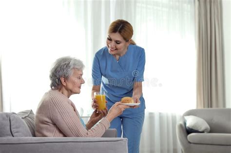 Nurse Serving Breakfast To Elderly Woman Indoors Assisting Senior