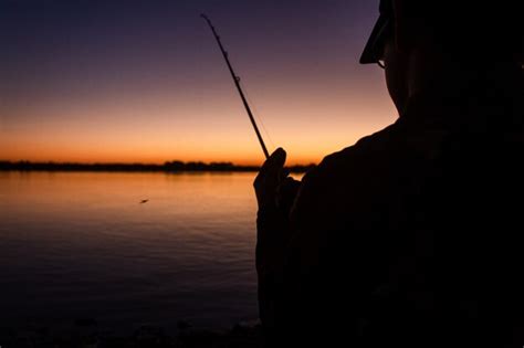Premium Photo Silhouette Of A Man Fishing On The Shore Of The River