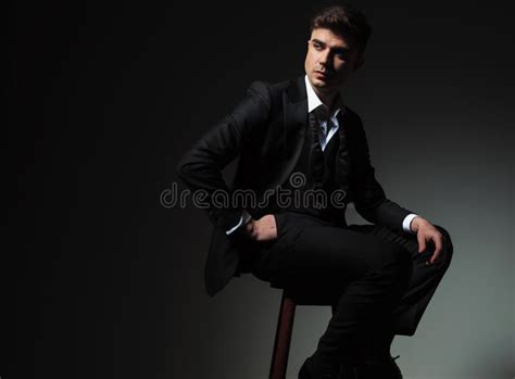 Side View Of Relaxed Seated Man In Tuxedo Looking Behind Stock Photo
