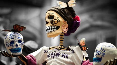 Download Dia De Los Muertos Skeleton Holding Skulls Wallpaper