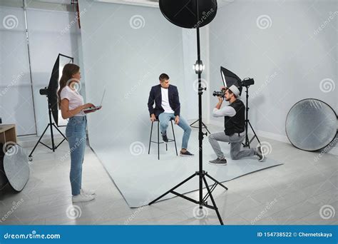 Professional Photographer Withassistant Taking Picture Of Young Man
