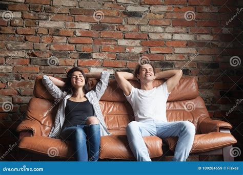 Young Happy Couple Relaxing On Comfortable Leather Couch At Home Stock