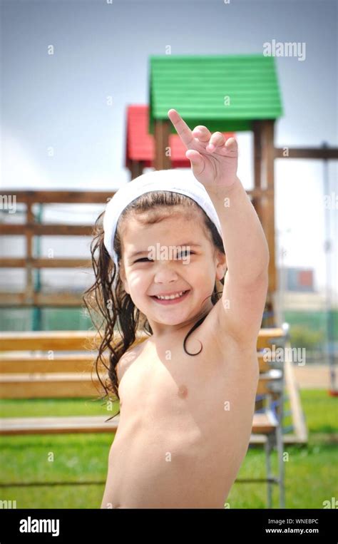 portrait of shirtless girl pointing in park against sky photo stock alamy