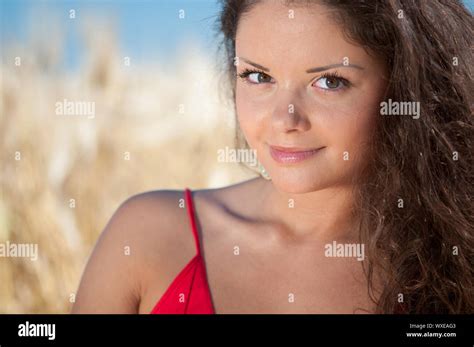 Beautiful Woman In Red Dress With Perfect Hair And Skin Posing In Wheat Field On Sunny Summer