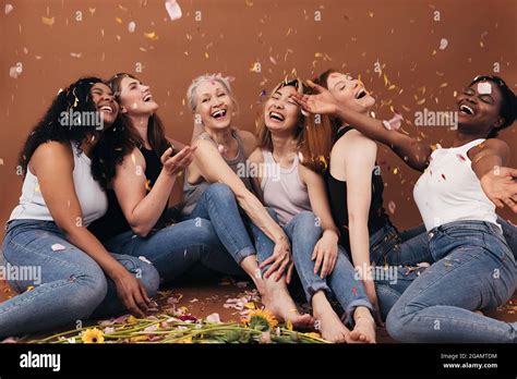 Group Of Six Laughing Women Of Different Ages Sitting Under Falling
