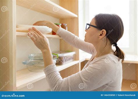 Adult Woman Picking Food From Storage Cabinet In Kitchen Storage With