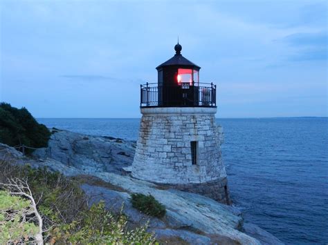 A Light House Sitting On Top Of A Rocky Cliff Next To The Ocean At Night