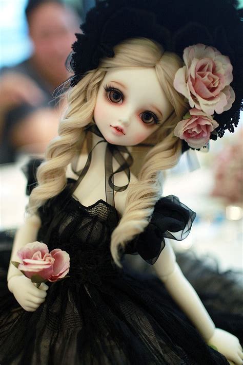 A Doll With Long Blonde Hair Wearing A Black Dress And Flowered Hat