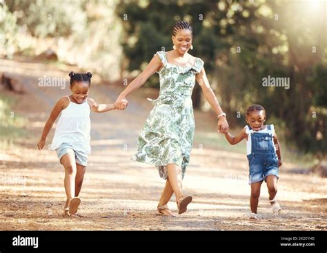 Happy Mother And Kids Walking In A Forest Holding Hands In Nature In