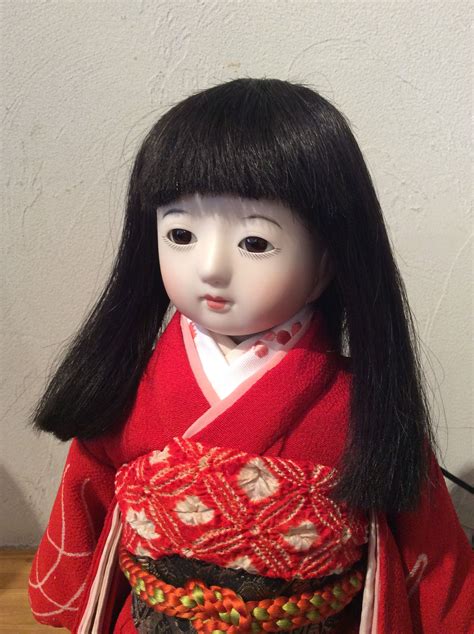 A Doll With Long Black Hair Wearing A Red Kimono