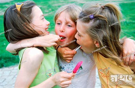 Three Young Girls Licking Lollipops With Their Arms Around Each Other