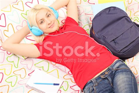Female Student Lying In Bed Listening To Music Stock Photo Royalty
