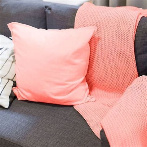 A Gray Couch With Pink And White Pillows Sitting On Its Backrests