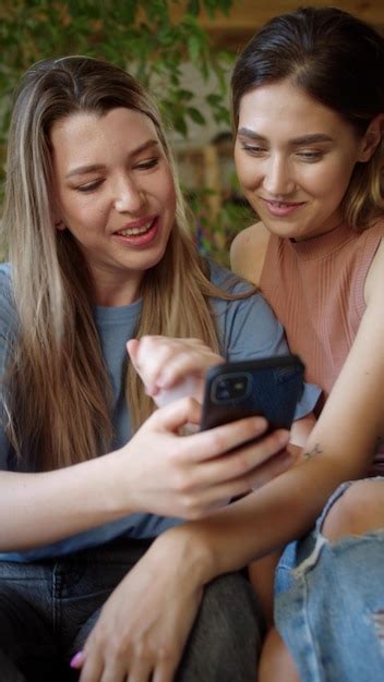 Premium Photo Smiling Lesbian Couple Looking At Mobile At Home