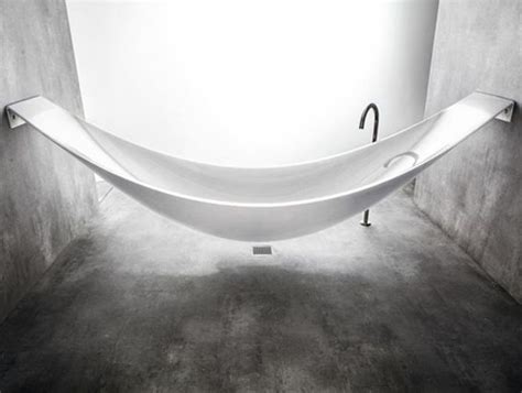 A White Bath Tub Sitting In A Bathroom Next To A Toilet Paper Dispenser