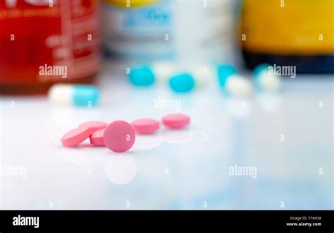 Round Pink Tablets Pill On Blurred Background Of Drug Bottle