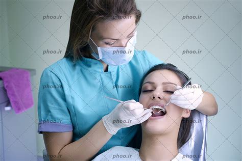 عکس با کیفیت دندان پزشک در حال معاینه دندان های زن زیبا به کمک آینه مقعر دندانپزشکی عکس با