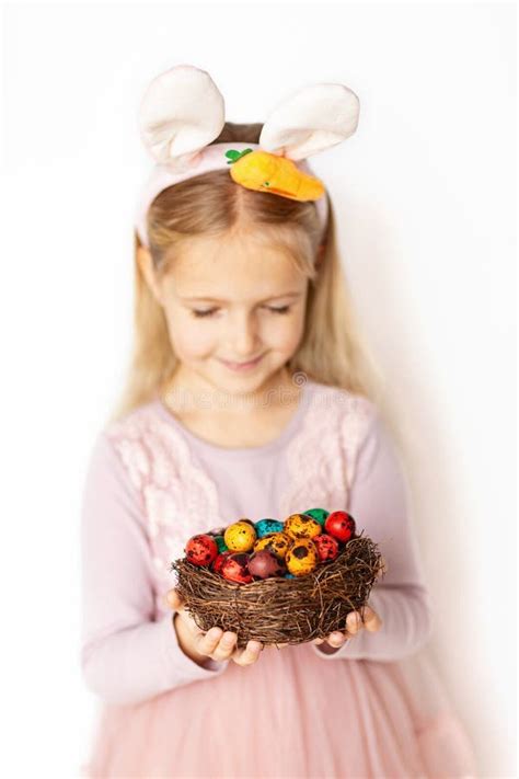 Cute Little Girl Holding Nest With Easter Eggs On White Background