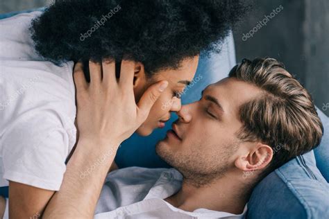 Young Multiracial Couple Kissing While Lying Sofa — Stock Photo 