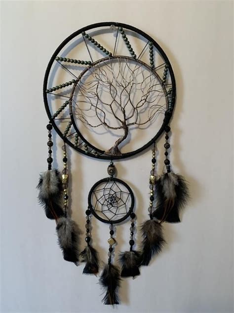 A Dream Catcher Hanging On The Wall Next To A Tree With Leaves And