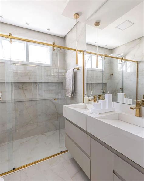 A Large Bathroom With Two Sinks And A Shower Stall In The Corner Along With Gold Fixtures
