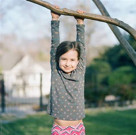 View Cute Young Girl Hanging On A Tree Branch By Stocksy Contributor