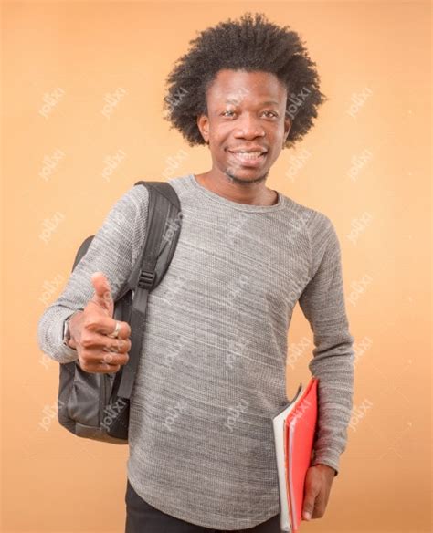 jeune étudiant africain souriant tenant ses cahiers avec son sac à dos sur un fond beige photo