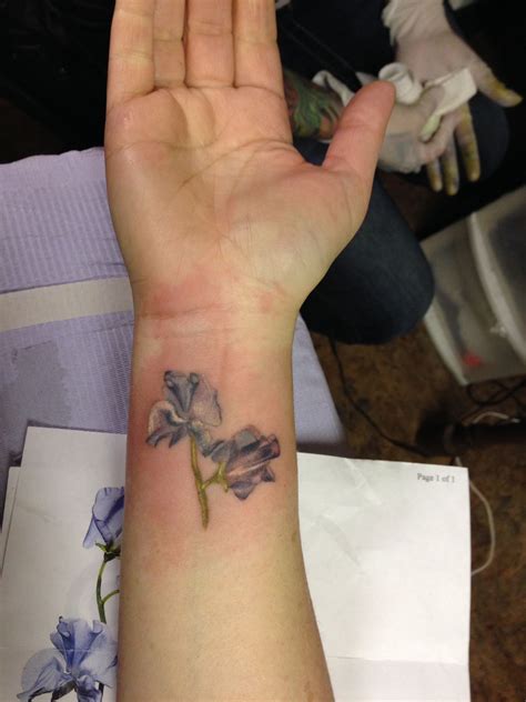 A Womans Hand With A Small Flower Tattoo On The Middle Of Her Arm