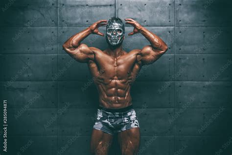 mysterious muscular man hiding behind mask flexing muscles bodybuilder with mask on his face