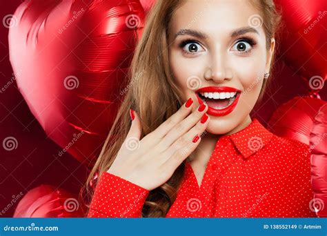 Surprised Woman With Red Lips Makeup And Manicured Hand On Red Heart Balloons Background