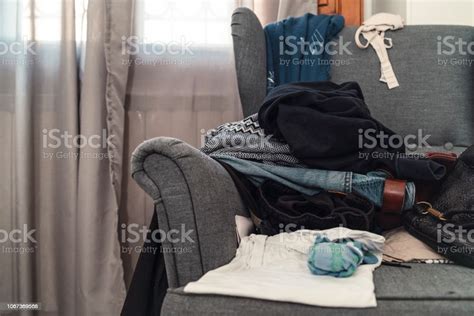 Messy Room With Scattered Clothes On The Armchair Stock Photo