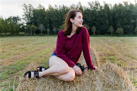 Beautiful Babe Brunette Sitting On A Bale Of Hay In The Country Side By Stocksy Contributor