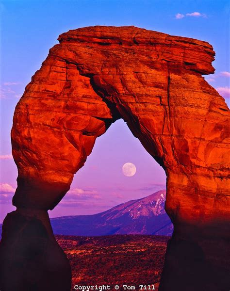 An Arch Shaped Rock Formation With The Moon In The Background