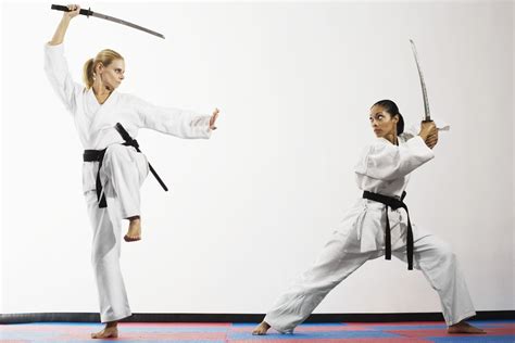 Two Women Are Practicing Karate In Front Of A White Wall