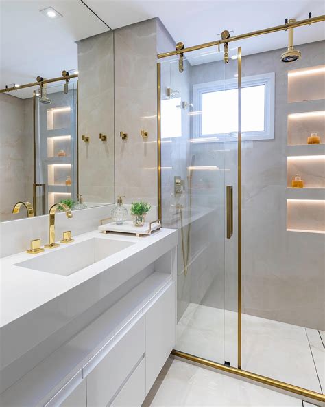 Banheiro contemporâneo com nichos iluminados e metais dourados Decor Salteado