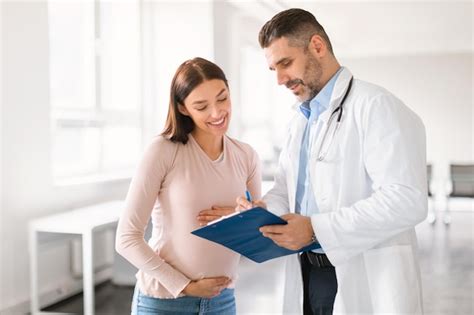 Médico masculino mostrando prancheta com resultados de exames médicos para grávida feliz durante