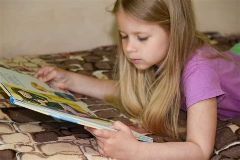 Premium Photo Child Girl Reading Book In Bed At Home