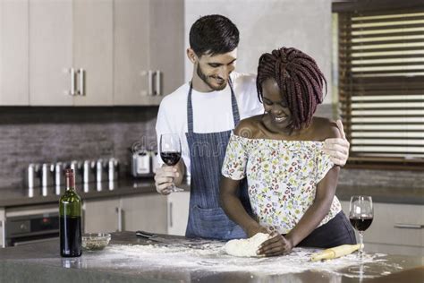 Happy Mixed Race Couple Kneading Dough Together In Kitchen Stock Photo