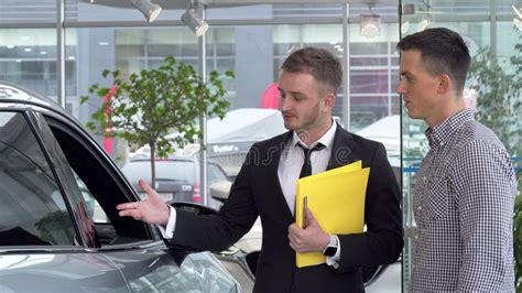 Friendly Car Dealer Helping His Male Customer Choosing Automobile To