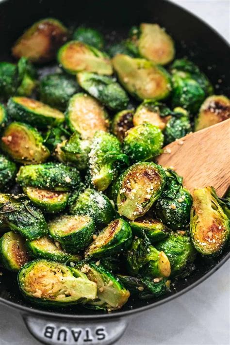 Brussel Sprouts Are Being Cooked In A Skillet With A Wooden Spoon