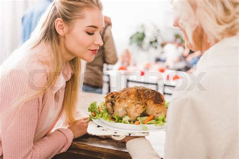 Mother And Daughter Holding Plate With Tasty Turkey In Thanksgiving Day