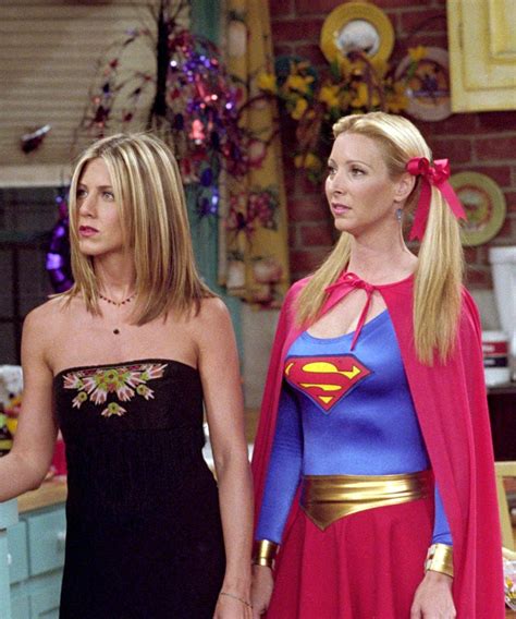 Two Women Dressed As Supergirls Standing Next To Each Other In A