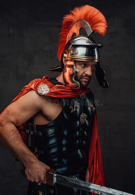 Roman Soldier With Red Mantle And Armour Posing With Sword Stock Photo
