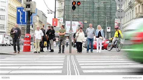 Pedestrians Waiting At Traffic Lights Busy Urban Street With Cars In