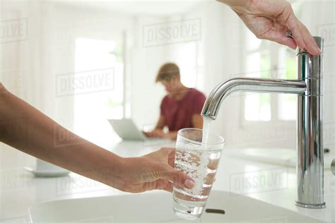 Woman Filling Glass Of Water At Kitchen Sink Cropped Stock Photo