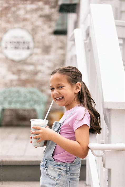 Young Girl Smiles To Camera While Enjoying A Milkshake Del