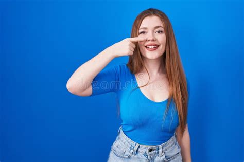 Redhead Woman Standing Over Blue Background Pointing With Hand Finger
