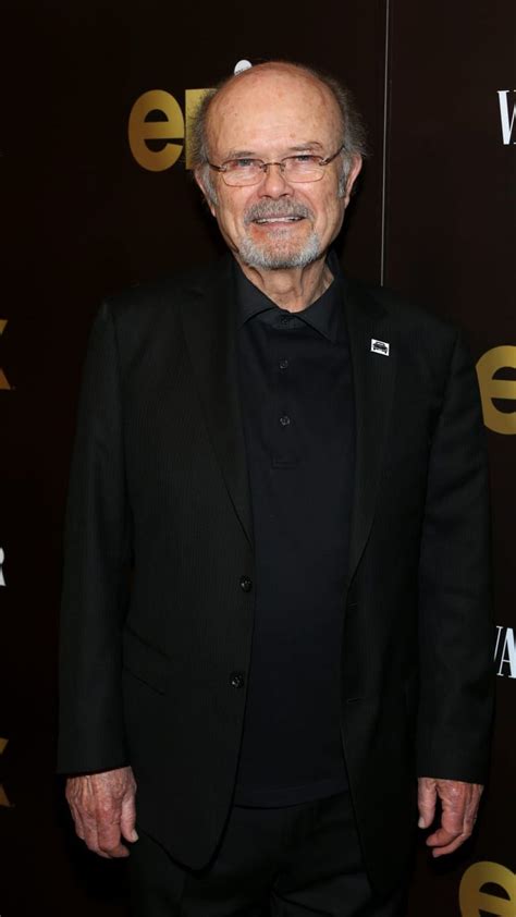 An Older Man In A Black Suit And Tie Posing For A Photo On The Red Carpet