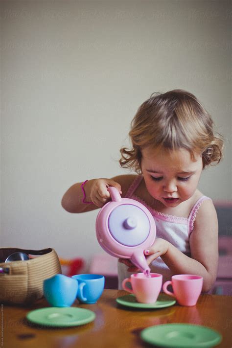 Cute Toddler Girl Carefully Pouring Tea At A Tea Party By Rob And Julia