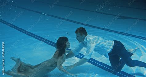 Man And Woman Swimming Underwater Towards Each Other And Emerging From